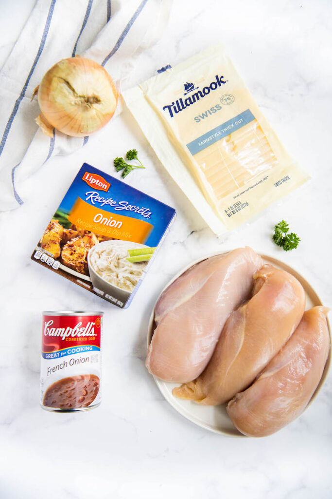 Ingredients arranged on countertop with chicken breasts on a plate.