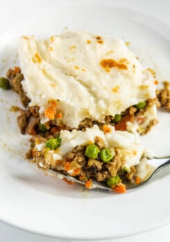 Shepherd’s pie on a white plate with a fork taking a bite out of it.