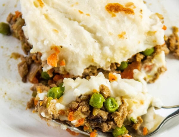 Shepherd’s pie on a white plate with a fork taking a bite out of it.