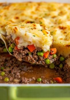 A portion of shepherd's pie is being lifted from a casserole dish.