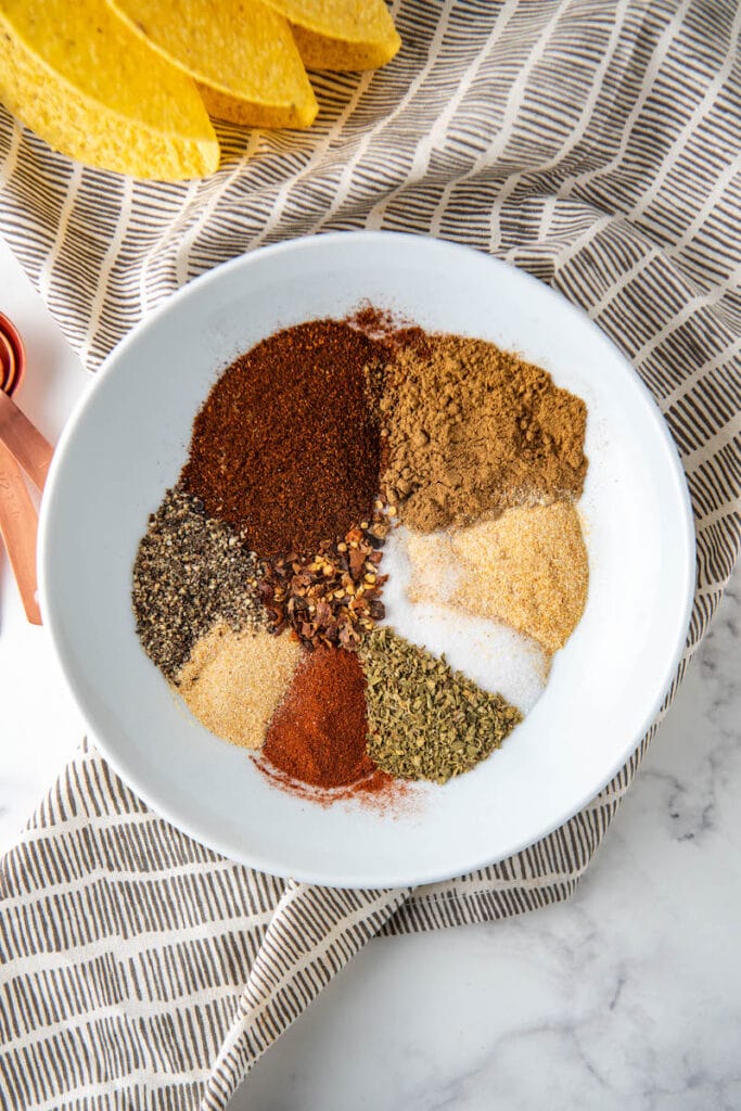 Taco seasonings in a white bowl on a tea towel.