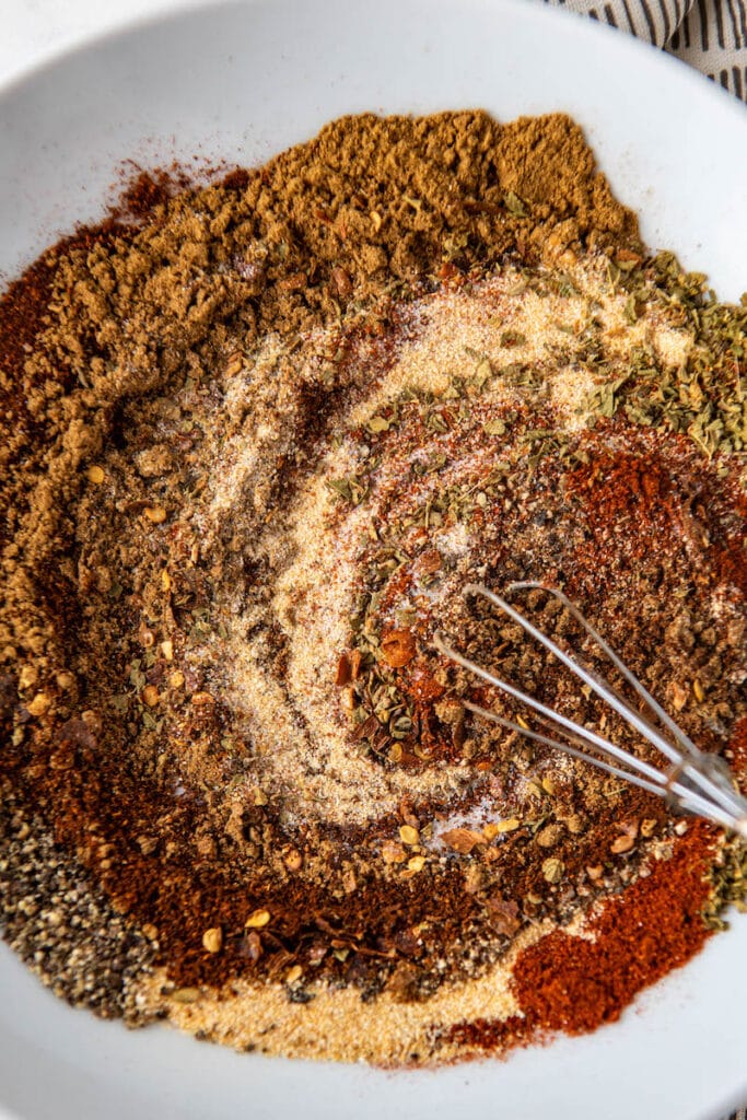 Taco seasonings mixed together in a bowl with a whisk.