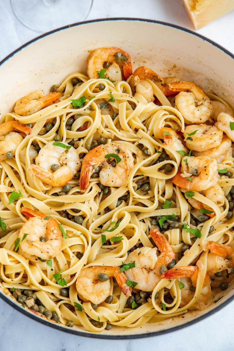 Shrimp Scampi tossed over pasta in a large pan.