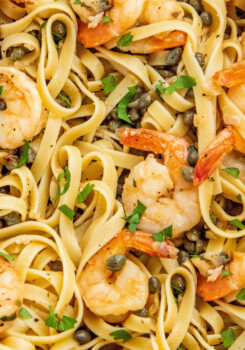 Up close image of Shrimp Scampi tossed with pasta and fresh parsley.