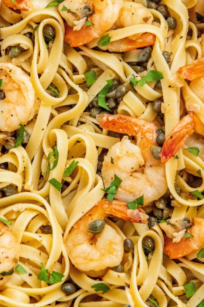 Up close image of Shrimp Scampi tossed with pasta and fresh parsley.