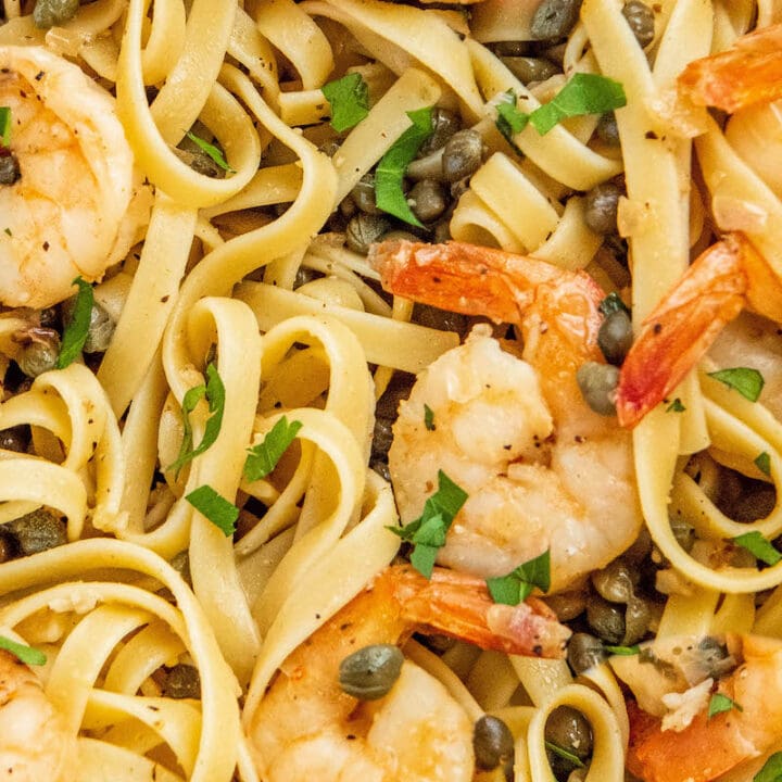 Up close image of Shrimp Scampi tossed with pasta and fresh parsley.