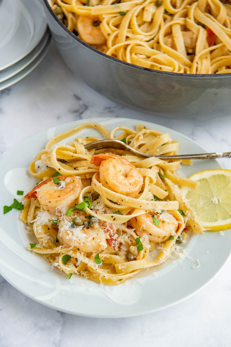 Shrimp Scampi with a slice of lemon on a plate with a fork.