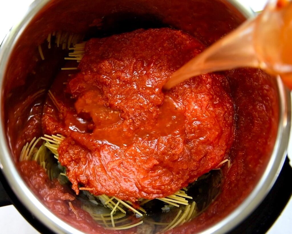 Marinara sauce is being poured into the pressure cooker.