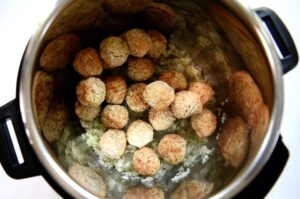 Frozen meatballs are laid in the bottom of the instant pot insert.