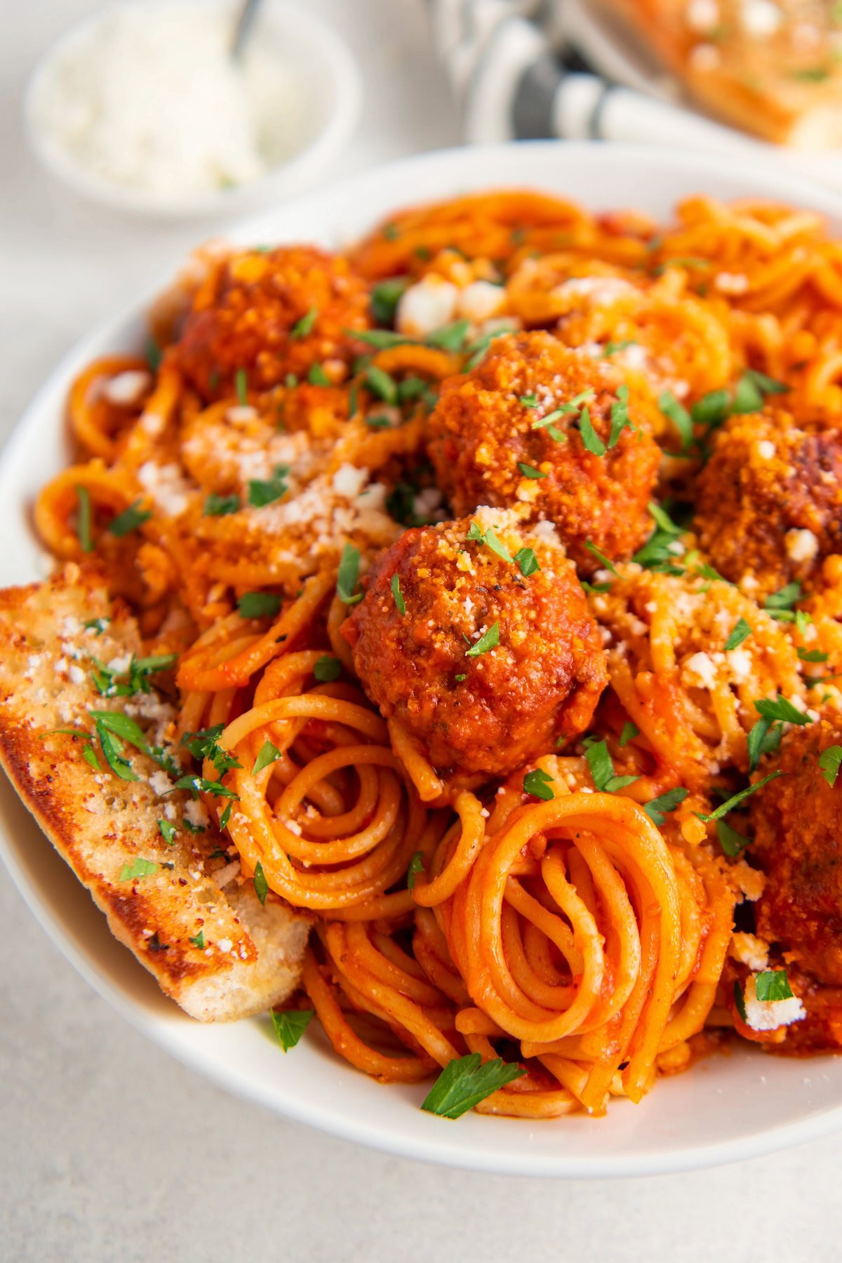 Ready in 30 minutes, Instant Pot Spaghetti and Meatballs transforms this classic dish into a one-pot meal! So easy, hands-free and less mess! Spaghetti and meatballs are served on a plate with garlic bread and fresh parsley.