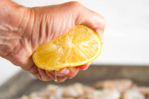 Lemon in a hand being squeezed with juice coming out.