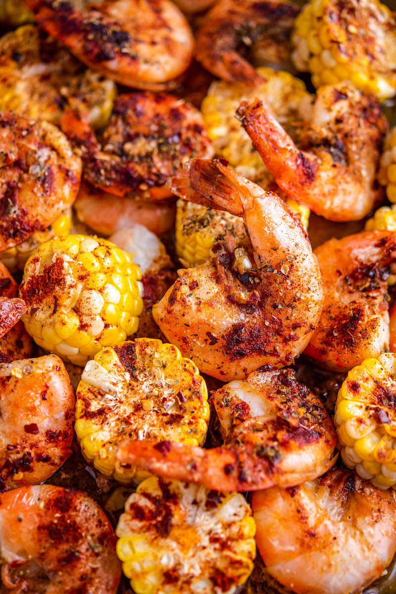 Cooked shrimp with corn and seasonings on a roasting pan.