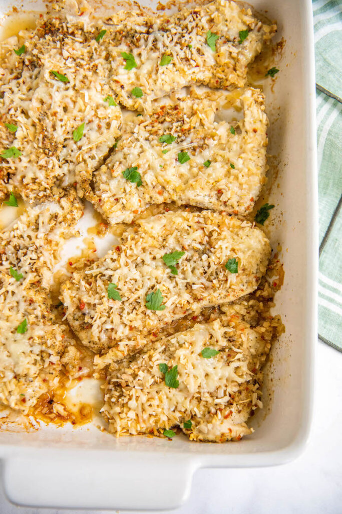 Cooked yum yum chicken in a casserole pan with parsley sprinkled on top.