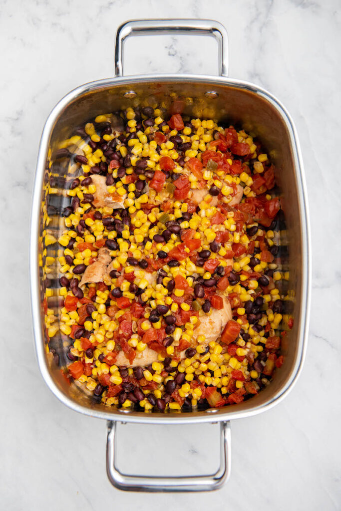 Overhead view of chicken, corn, black beans and salsa in a crockpot. 