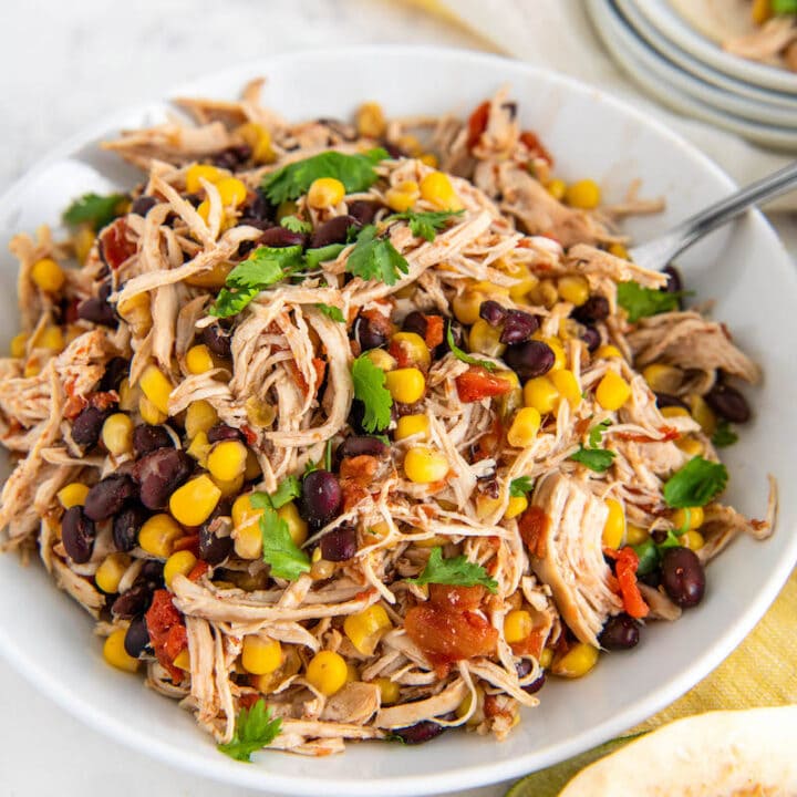 Crockpot Mexican Chicken in a white bowl with cilantro on top with a fork.