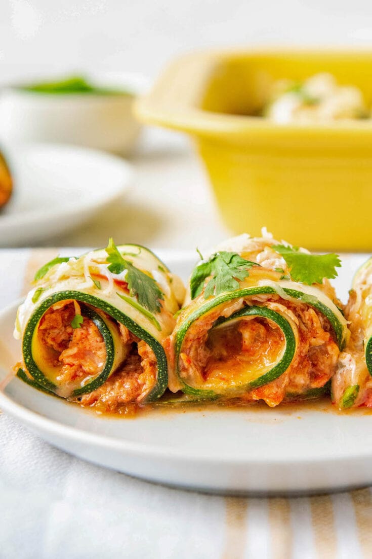 Zucchini rolled with chicken and cheese on a plate.