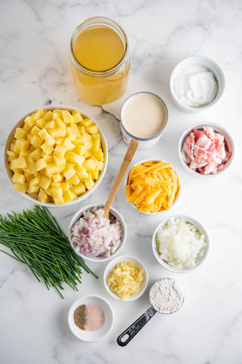 The ingredients for potato soup are displayed on a white surface 