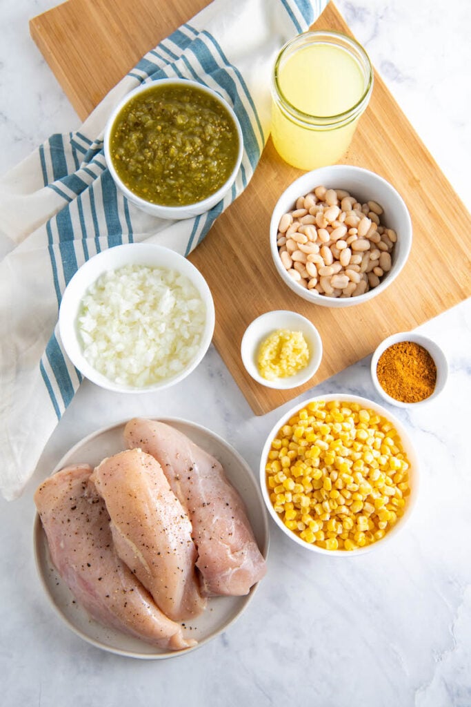 Ingredients for chicken soup in bowls and on a cutting board.