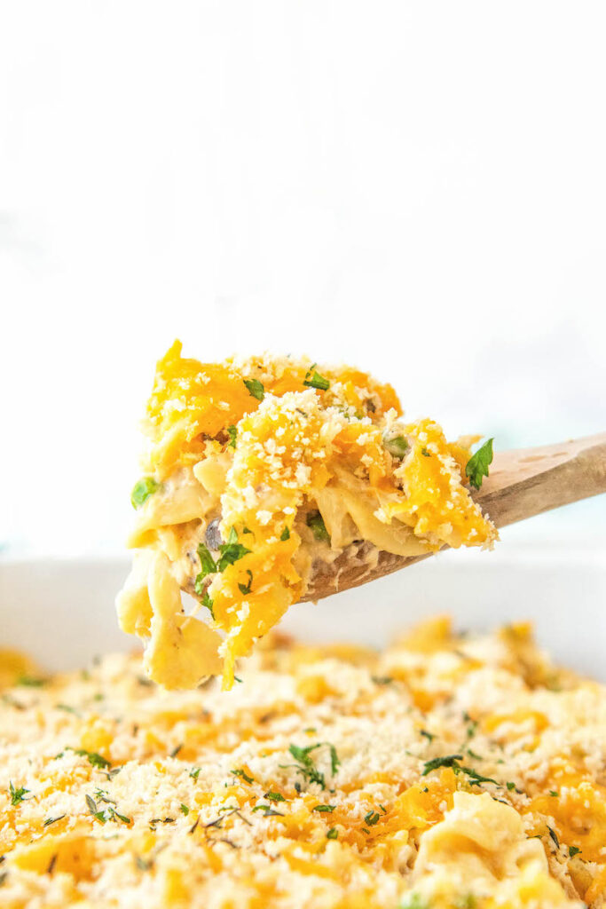 A wooden spoon is holding a dollop of tuna noodle casserole.