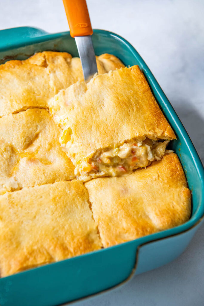 A piece of Cajun Chicken casserole is being taken out of the dish