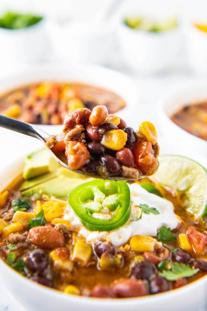 A spoonful of taco soup is lifted out of a full bowl