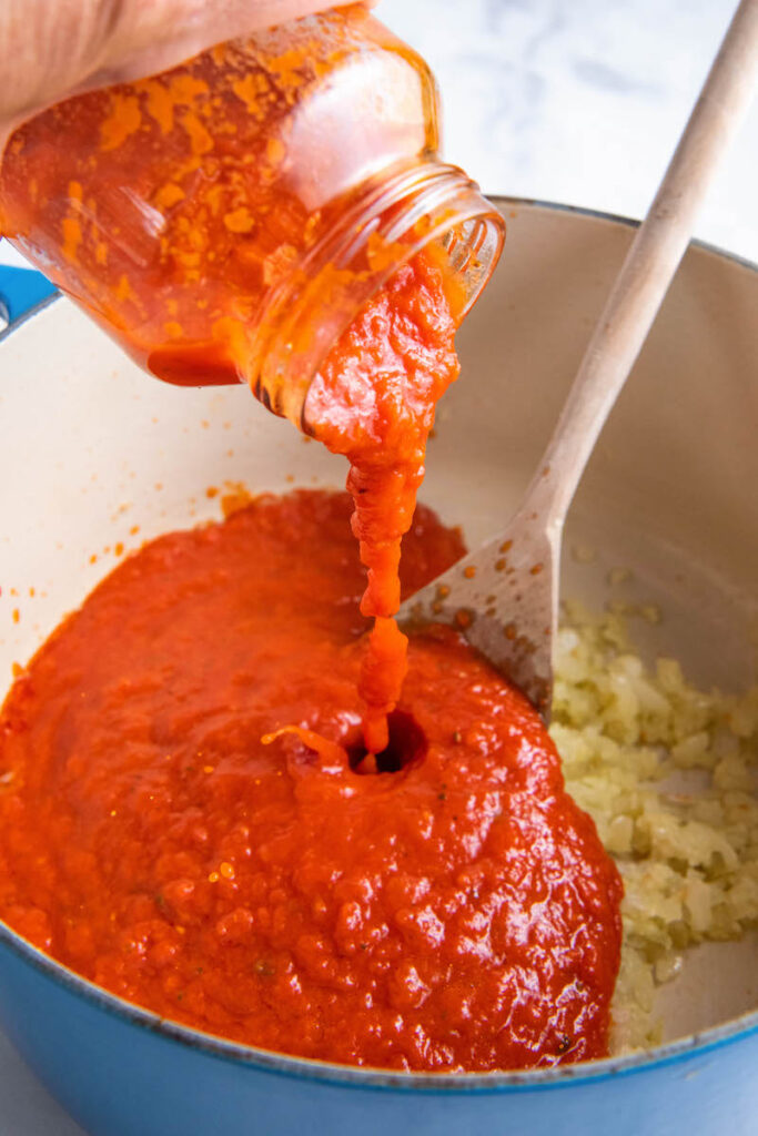 Marinara sauce is poured into the dutch oven