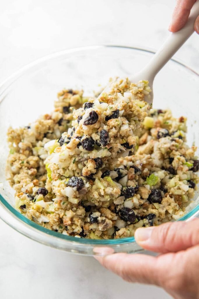 Stuffing is being stirred together with a wooden spoon.