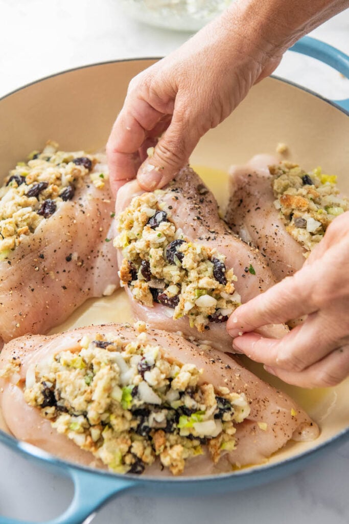 Raw chicken breasts stuffed with stuffing are placed in a prepared baking dish.