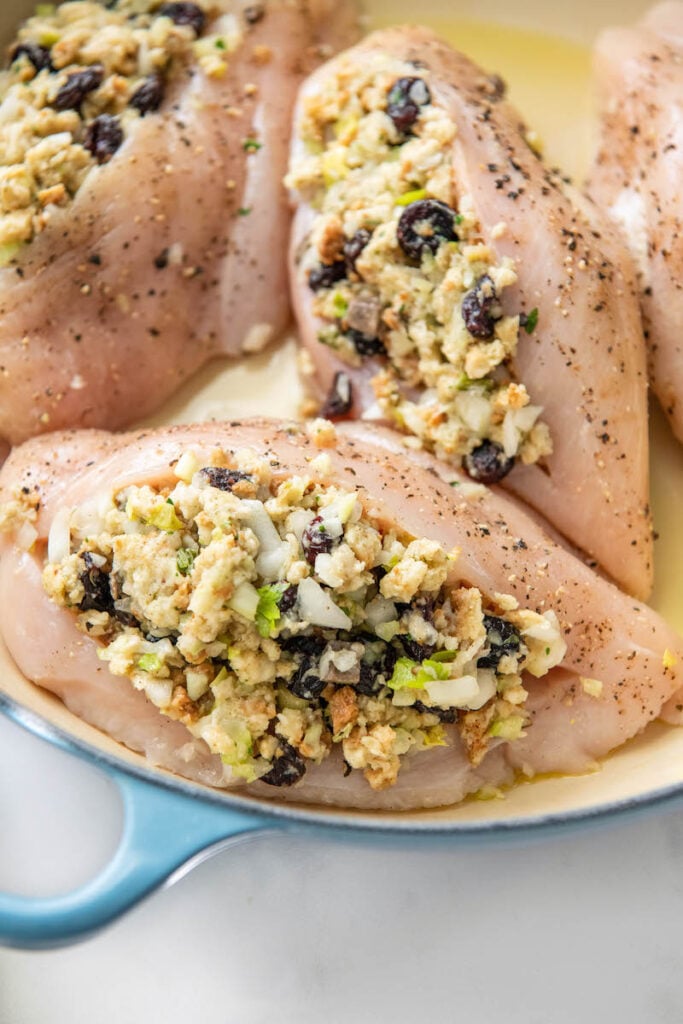 Two raw, stuffed chicken breasts are in a blue baking dish.