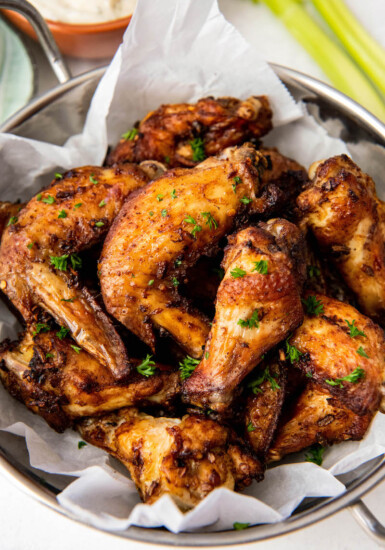 A pile of cooked wings sit on a white sheet of parchment paper.