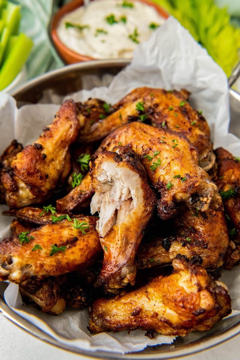 A bite has been taken out of am air fryer chicken wing, revealing the perfectly cooked white meat.