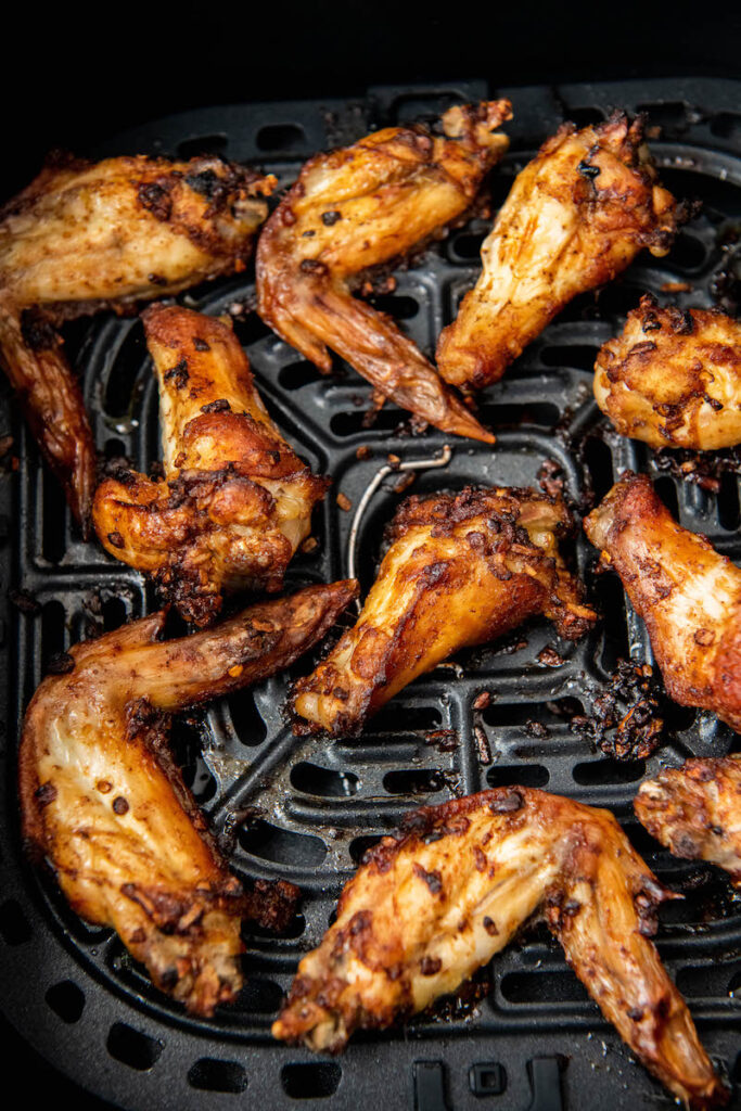 Cooked wings sit in the bottom of an air fryer.