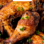 Chicken Wings on a plate with green herbs on top.