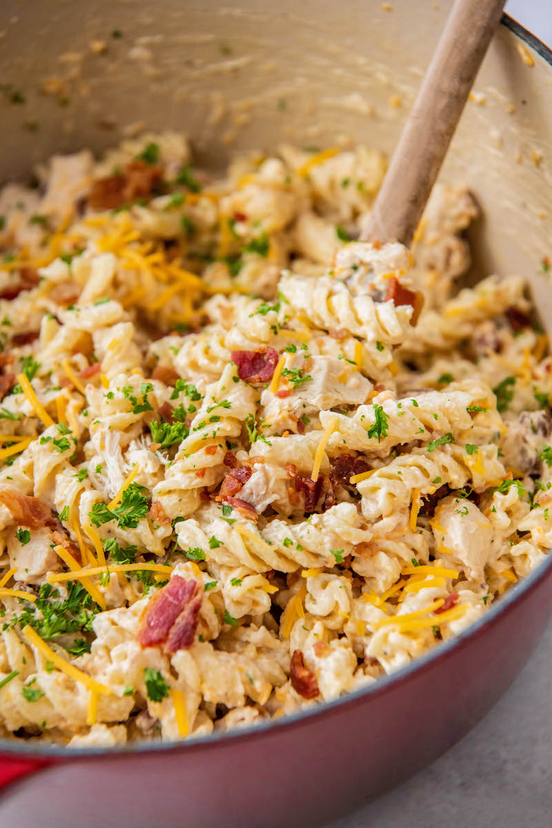 A finished pot of chicken bacon ranch pasta is in a large red pot, ready to be served.