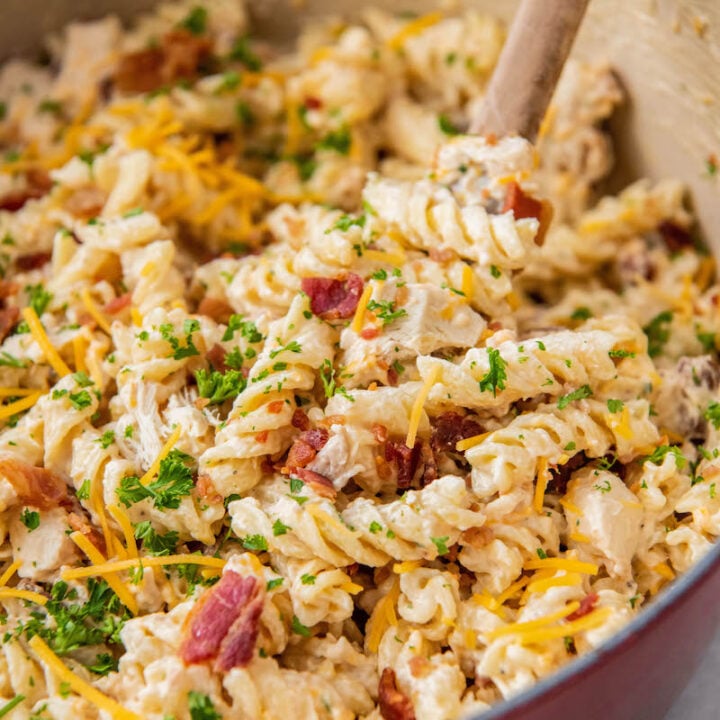 A large pot is filled with rotini noodles, bacon, and sauce.