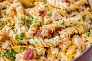 Up close image of creamy ranch pasta tossed with chicken, cheese, bacon and parsley on top.