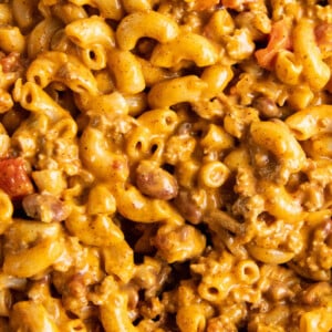 Elbow noodles are coated in yellow cheese mixed with brown ground beef.