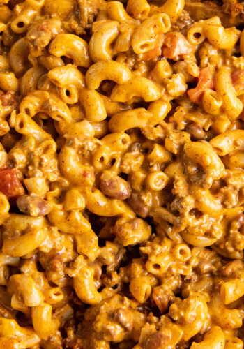 Elbow noodles are coated in yellow cheese mixed with brown ground beef.