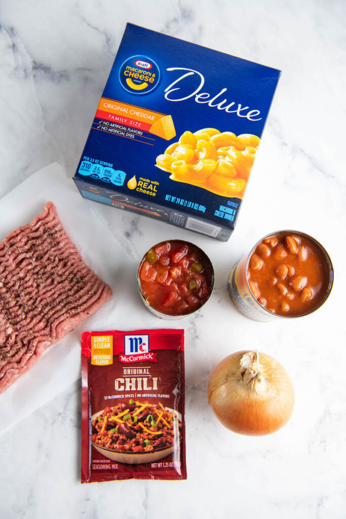 The ingredients for chili mac are separated on a white countertop.