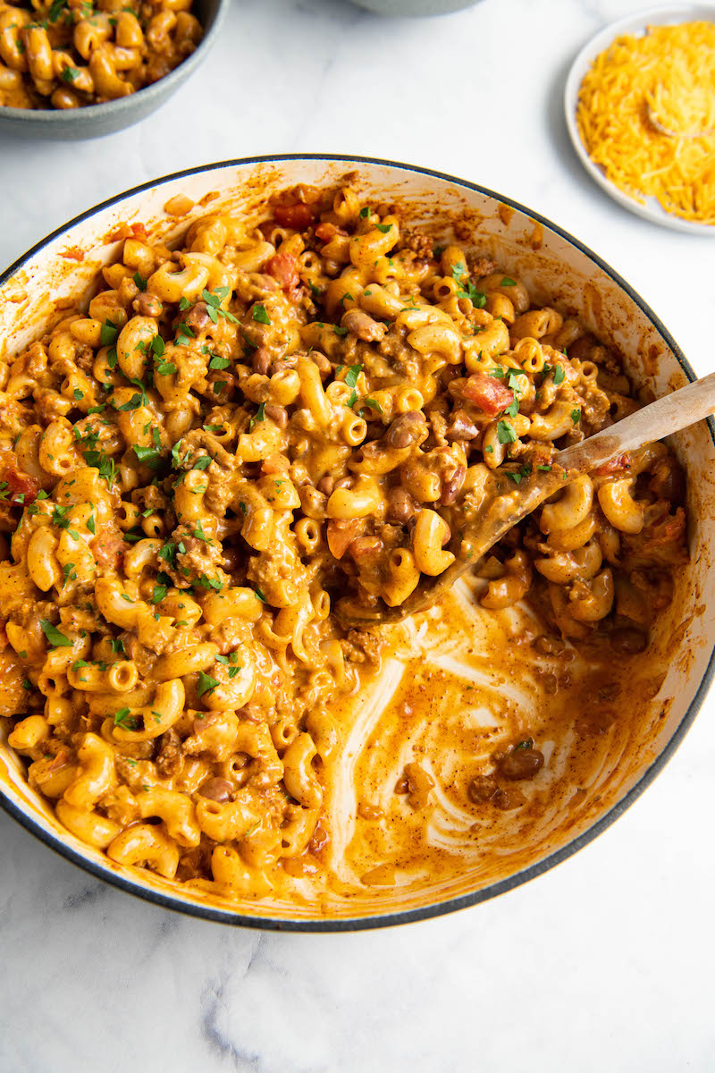 A skillet has a portion of chili mac missing.