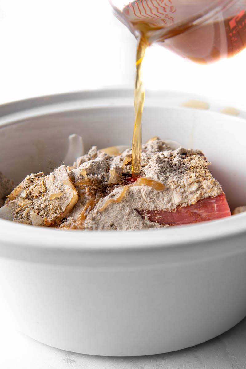 Beef broth is poured on top of the gravy mix and meat in the Crockpot.