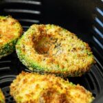 Crispy, golden brown air fried avocado halves in an air fryer basket.