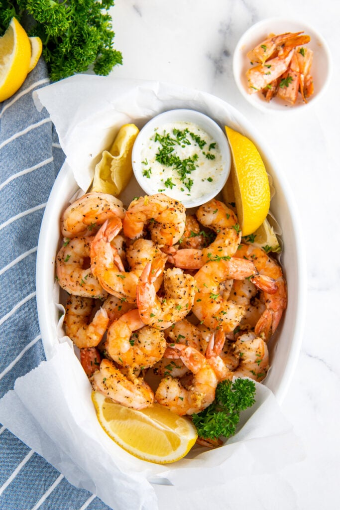 Air fryer shrimp are presented in a white serving bowl and are ready to eat.