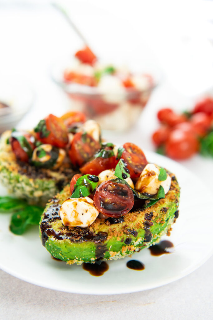 Two avocados are presented on a white plate, ready to be eaten.