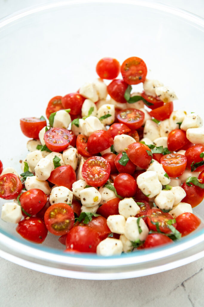The fresh caprese ingredients are mixed together in a glass bowl.