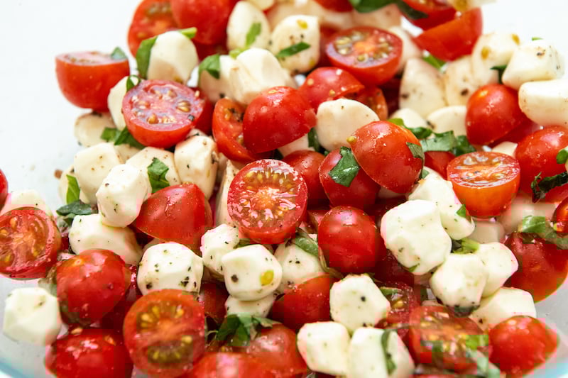 Caprese Salad tossed together in a glass bowl.
