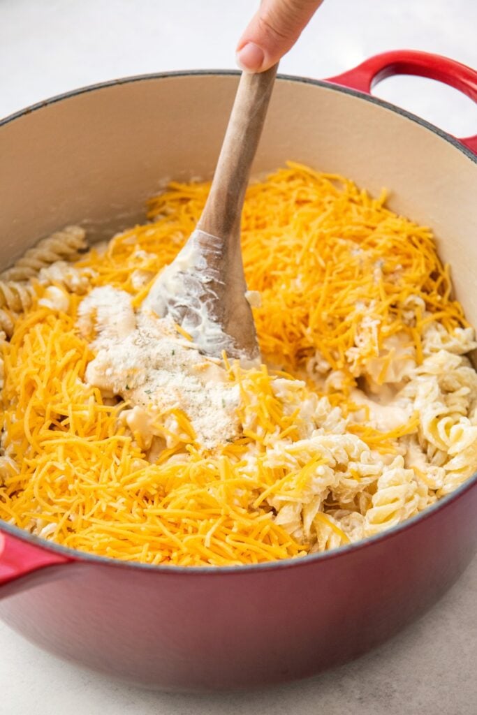 Shredded cheese is being mixed into the pot.