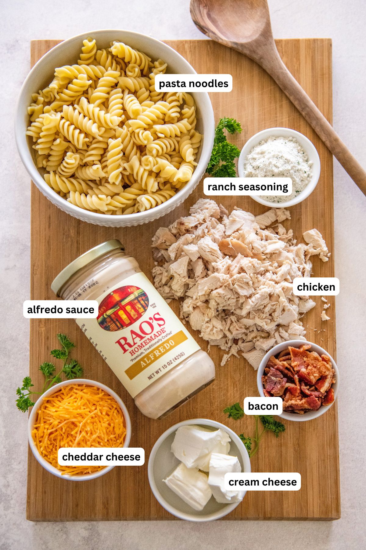 The ingredients for chicken bacon ranch pasta recipe in order from top to bottom: pasta, ranch seasoning, alfredo sauce, chicken, cheddar cheese, cream cheese and bacon.