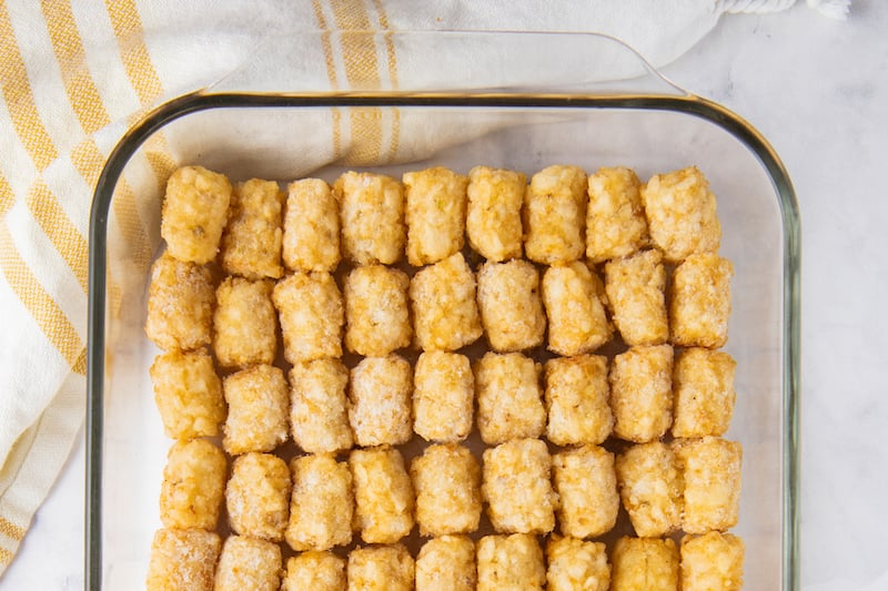 Overhead image of tater tots lined in a glass casserole dish.
