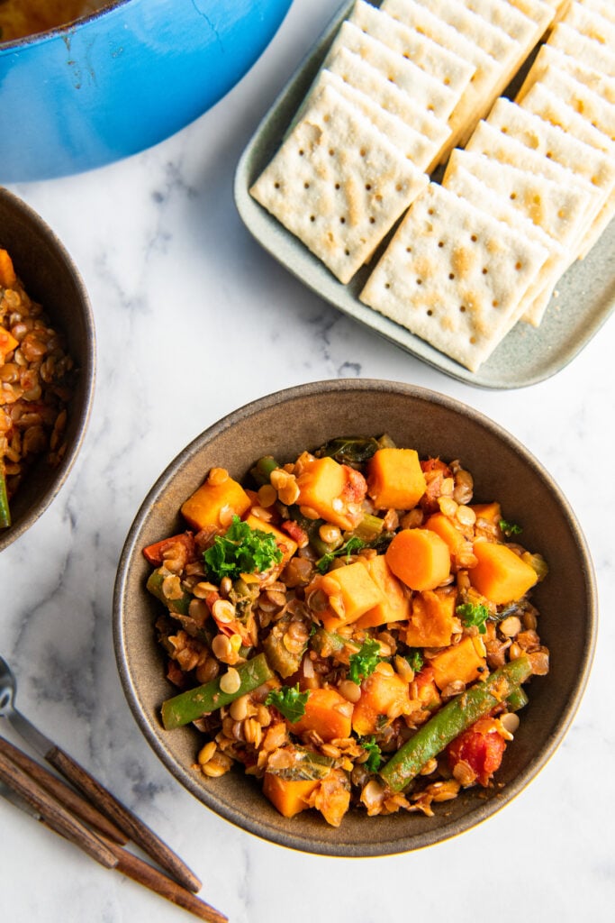 Saltine crackers are placed next to a bowl of lentil stew.